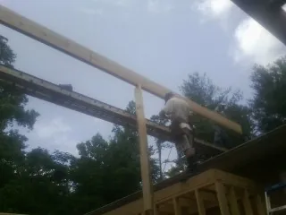 Carpenter setting a ridge beam over a new addition frame — Ice Dam Removal by Roofing Brothers in Preble