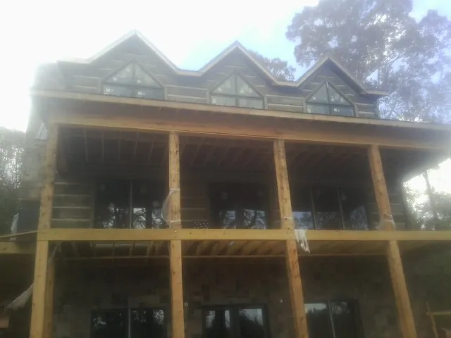 Dormers and porch framing on a large log home under construction — Roof Coating work by our crew in Preble