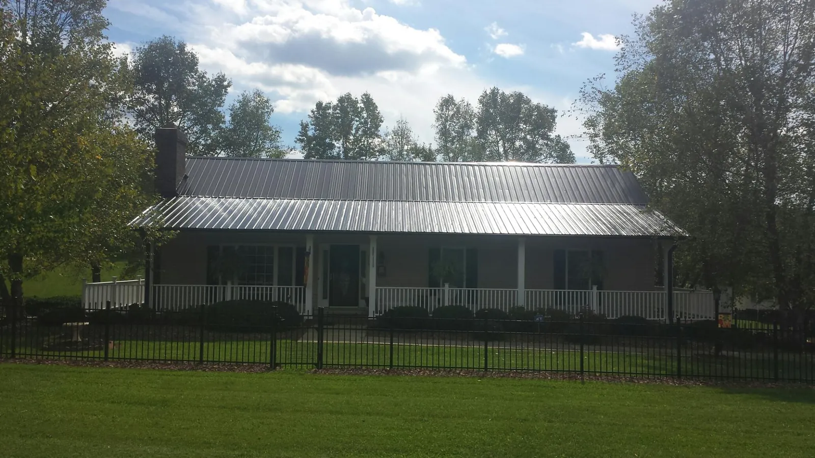 Gray metal roof on a brick ranch with a full width front porch — Gutter Guard Installation work by our crew in Preble