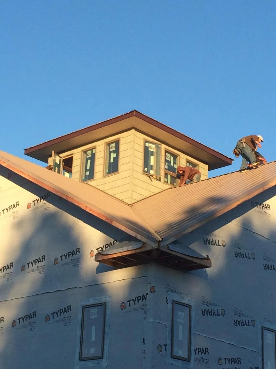 Roofers working around a rooftop cupola on a new metal roof at sunset — Roof Waterproofing in Preble by Roofing Brothers